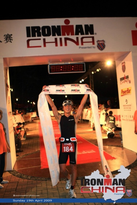 Male athlete holds up finishing banner at Ironman China