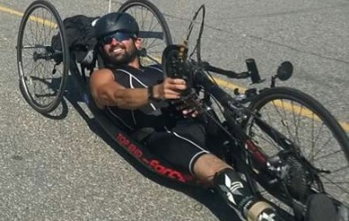 Athlete smiles and races in a handcycle in a triathlon.