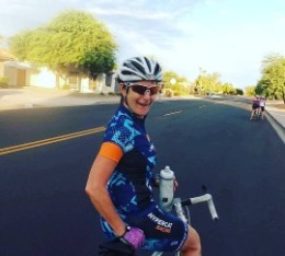 Women smiles while holding water bottle sitting on her bike.