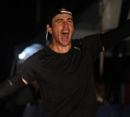 Male triathlete triumphantly crosses the Ironman finish line